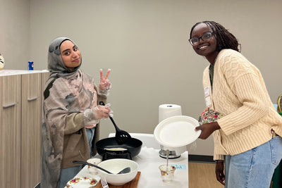 Two women in a kitchen setting with cooking utensils and ingredients.